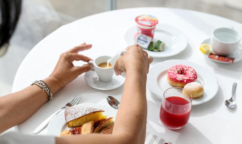 Frühstück mit Kaffee, Gebäck und Saft auf weißem Tisch.