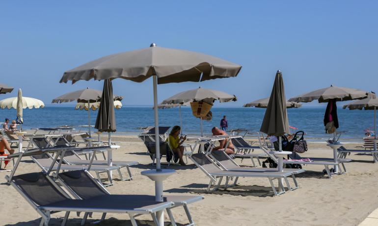 Strand mit Liegen und Sonnenschirmen, ruhiges Meer.