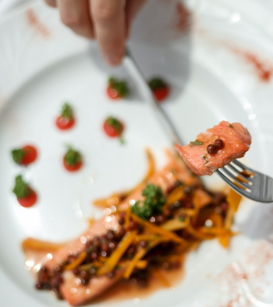 Piatto di salmone con verdure e salse, decorato con erbe e spezie.